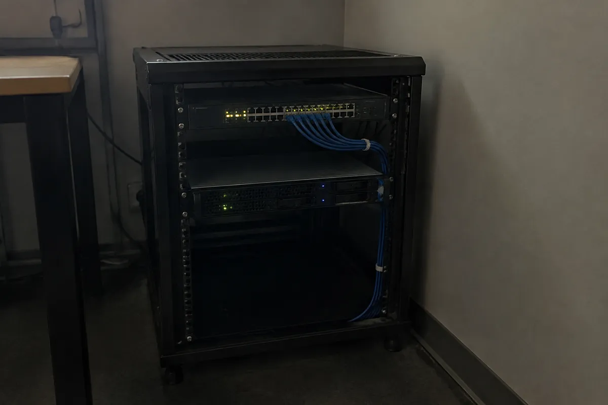 a small server rack with a couple of rackmount units and blinking LEDs, neat cabling, dim room light