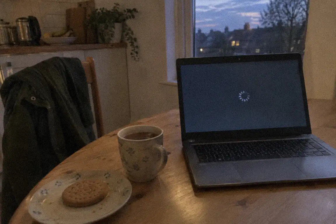 a small community office with a shared desk, a laptop and a kettle in the background